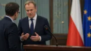 Wyłączony mikrofon na pulpicie, w tle rozmyta rozmowa polityków